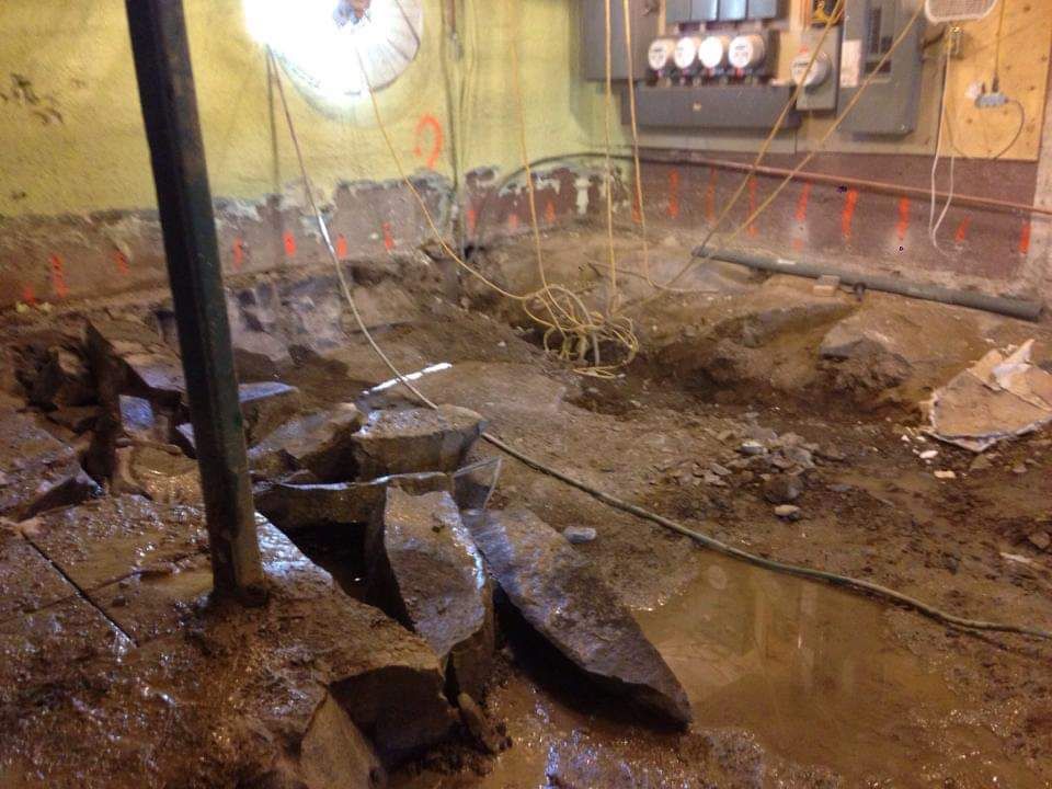 Un sous-sol inondé avec beaucoup de cailloux et de l'eau qui en sort.