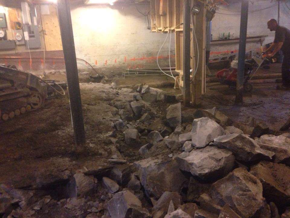 Un chantier de construction avec beaucoup de rochers et un bulldozer en arrière-plan.