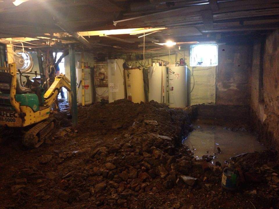 Une excavatrice jaune creuse un trou dans un sous-sol.