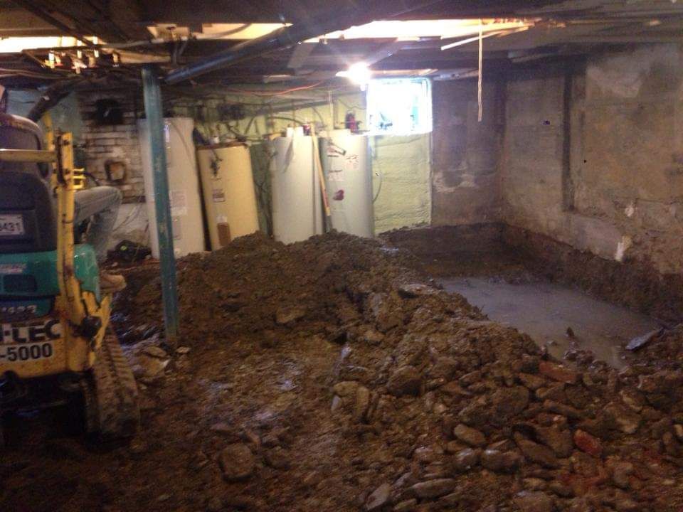 Une excavatrice jaune déplace de la terre dans un sous-sol.