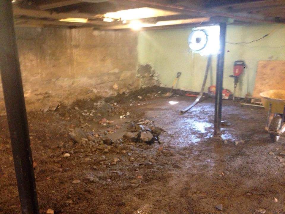 Une cave sale avec une brouette et un aspirateur.