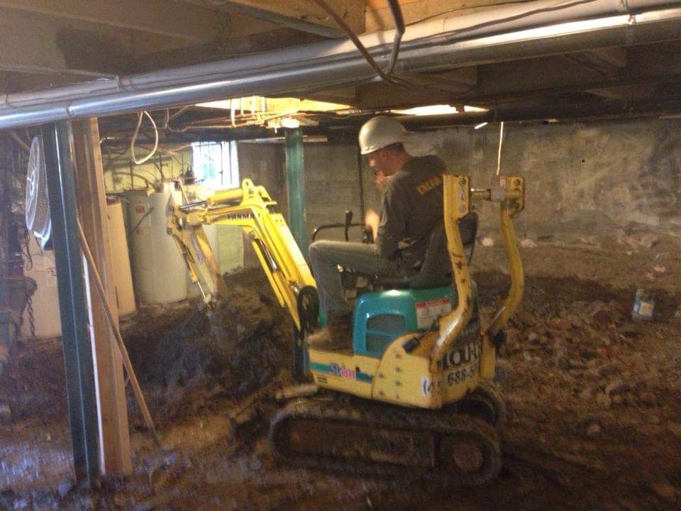 Un homme conduit une petite pelle jaune dans un sous-sol.
