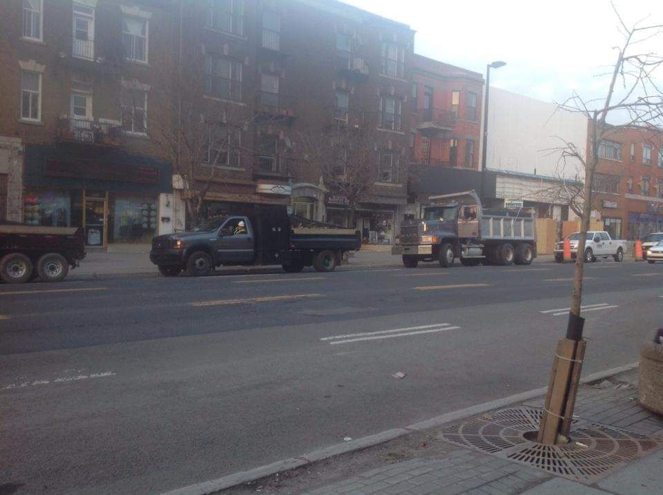 Un camion-benne est garé sur le bord de la route devant un immeuble.