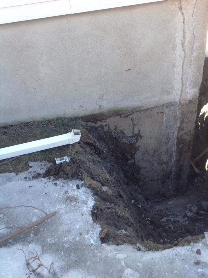 Un trou dans le sol à côté d'un mur avec un tuyau qui en sort.