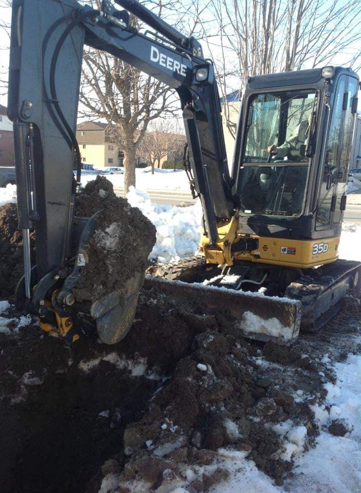 Une excavatrice Deere creuse un trou dans la neige.