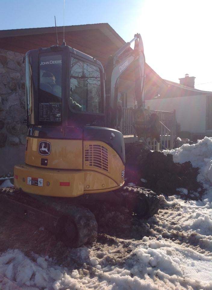 Une pelle jaune est garée dans la neige devant une maison.