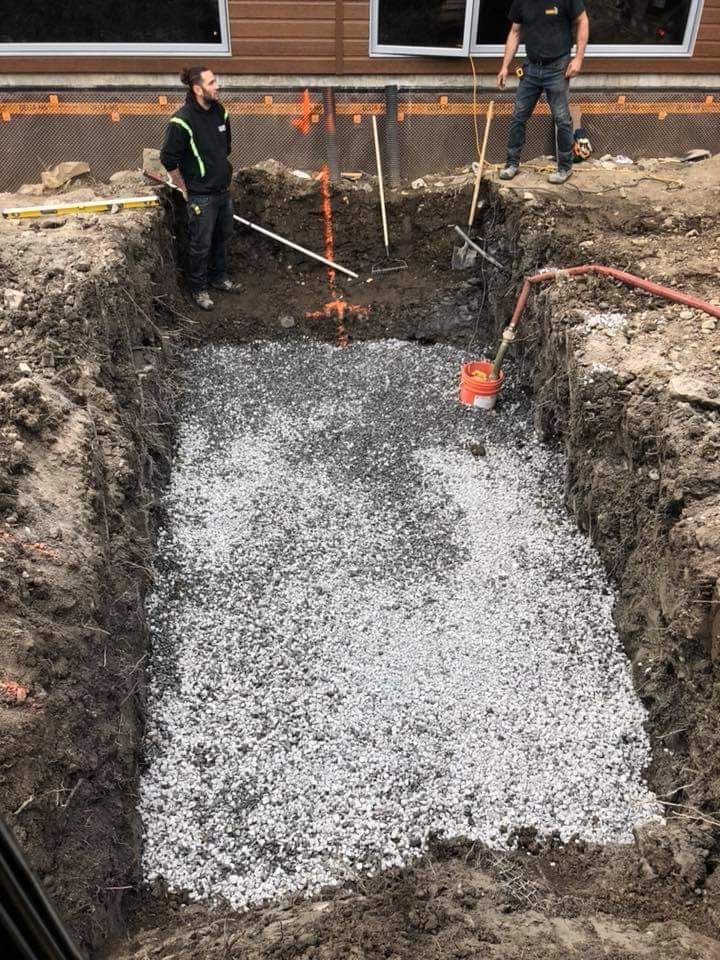 Deux hommes se tiennent dans un grand trou dans le sol.