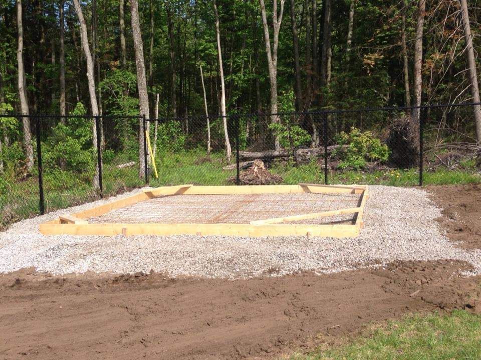 Une structure en bois est en cours de construction au milieu d'un champ de terre.
