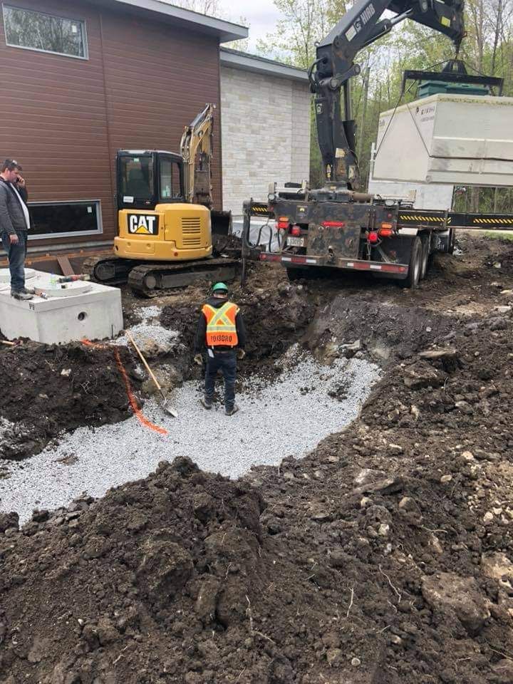 Un ouvrier du bâtiment se tient dans la terre devant une excavatrice à chat.