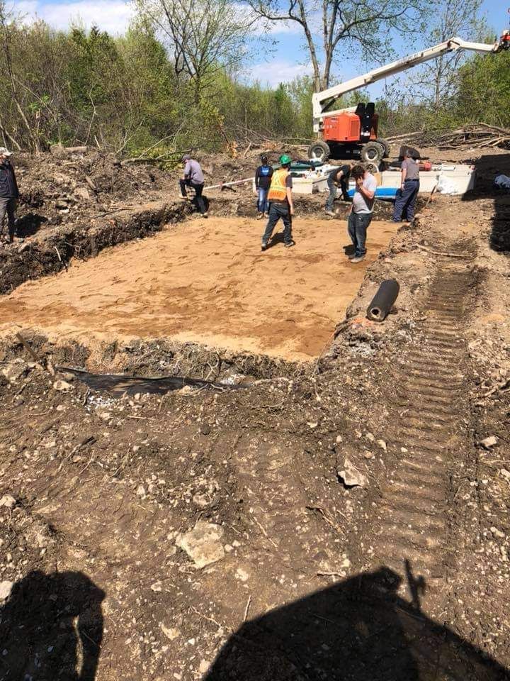Un groupe de personnes travaillent sur un champ de terre.