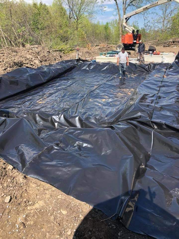 Un homme se tient debout sur un gros morceau de plastique noir.