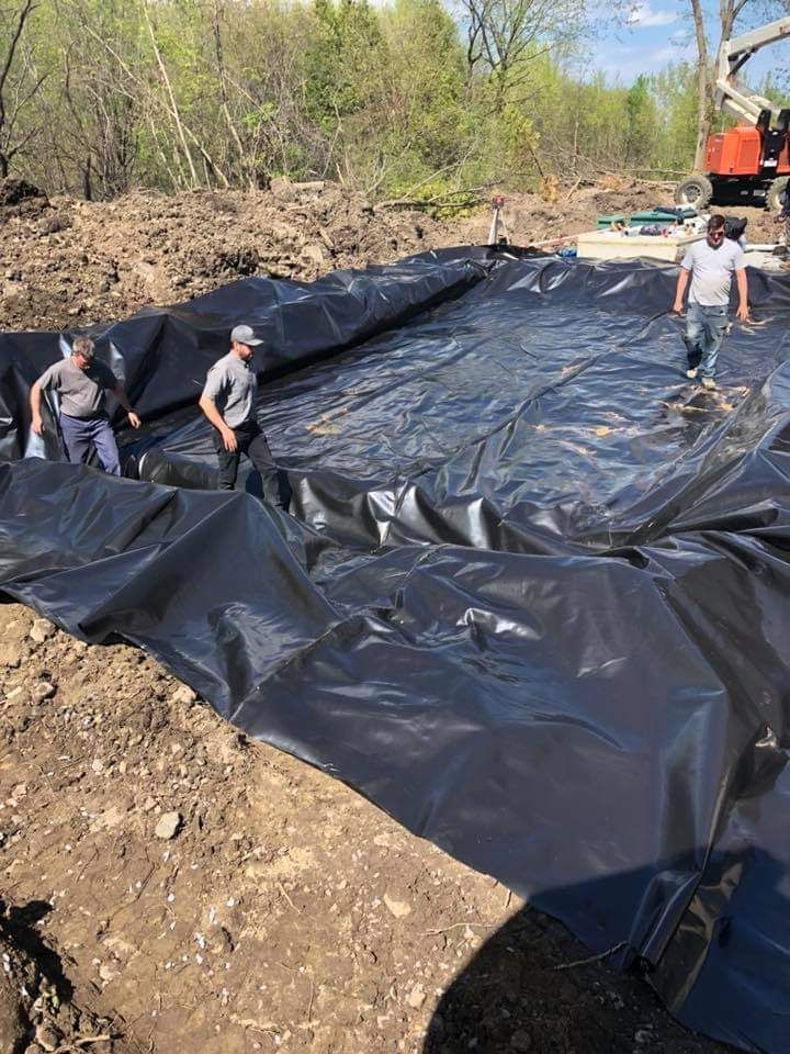 Un groupe de personnes se tient au sommet d’une grande bâche noire.