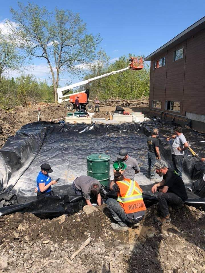 Un groupe d'ouvriers du bâtiment travaillent dans la terre devant une maison.