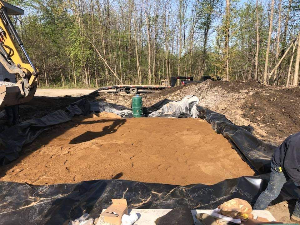 Un homme est agenouillé dans un tas de terre à côté d'un bulldozer.