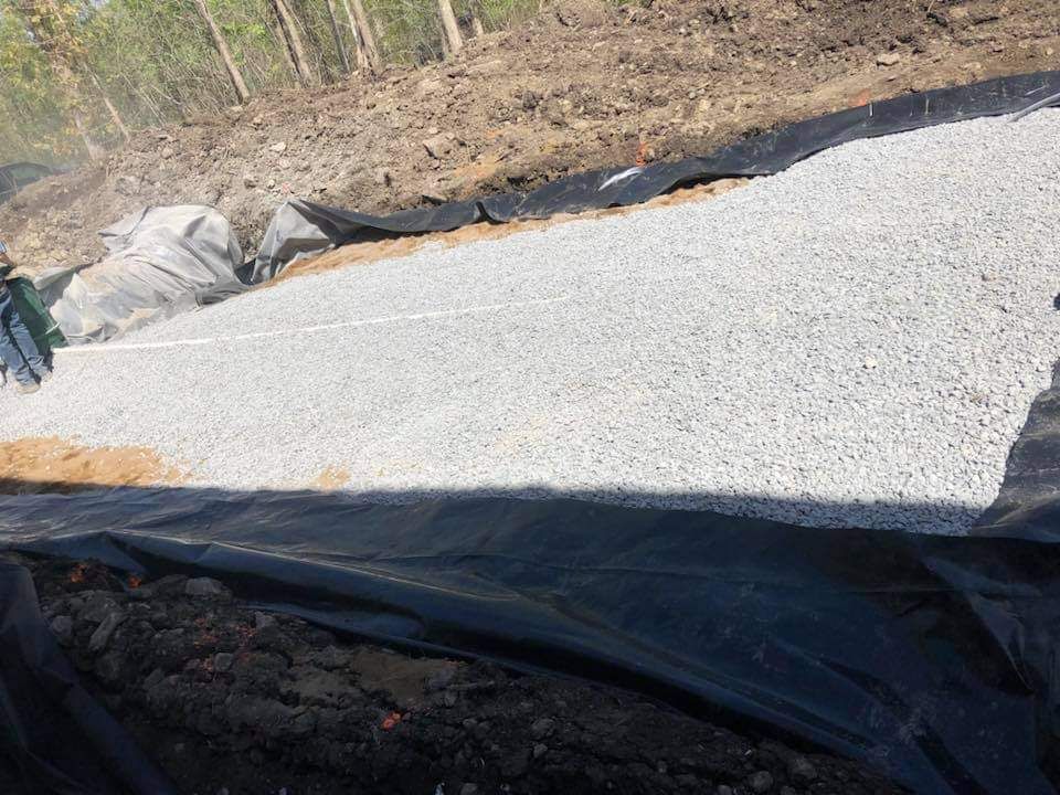 Un tas de gravier se trouve au sommet d’un chemin de terre.