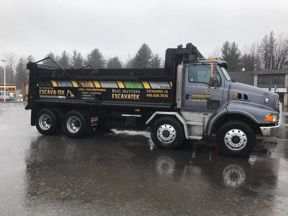 Un camion à benne basculante est garé dans un parking un jour de pluie.