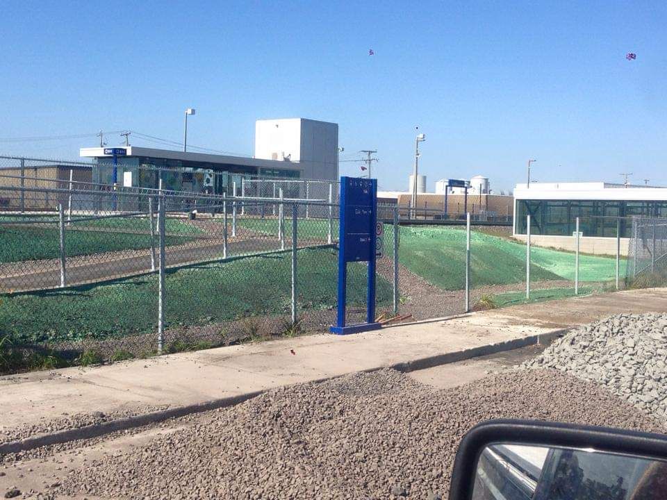 Une zone clôturée avec un panneau bleu au premier plan