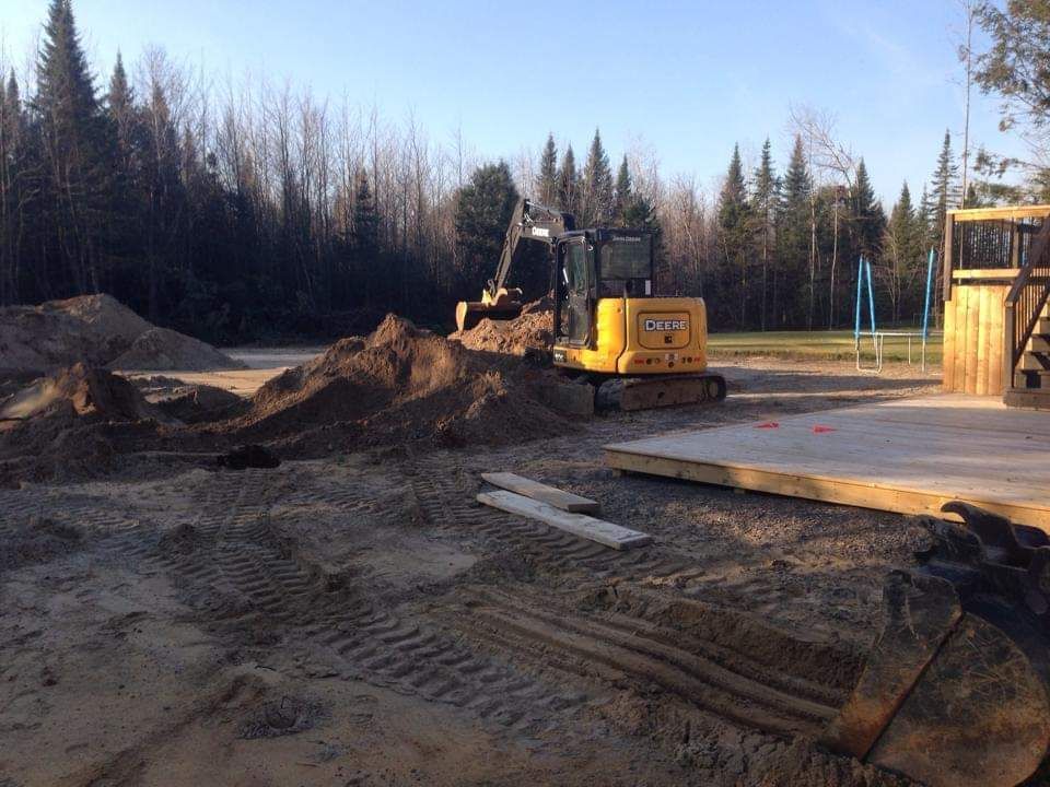 Une excavatrice jaune creuse un trou dans la terre.