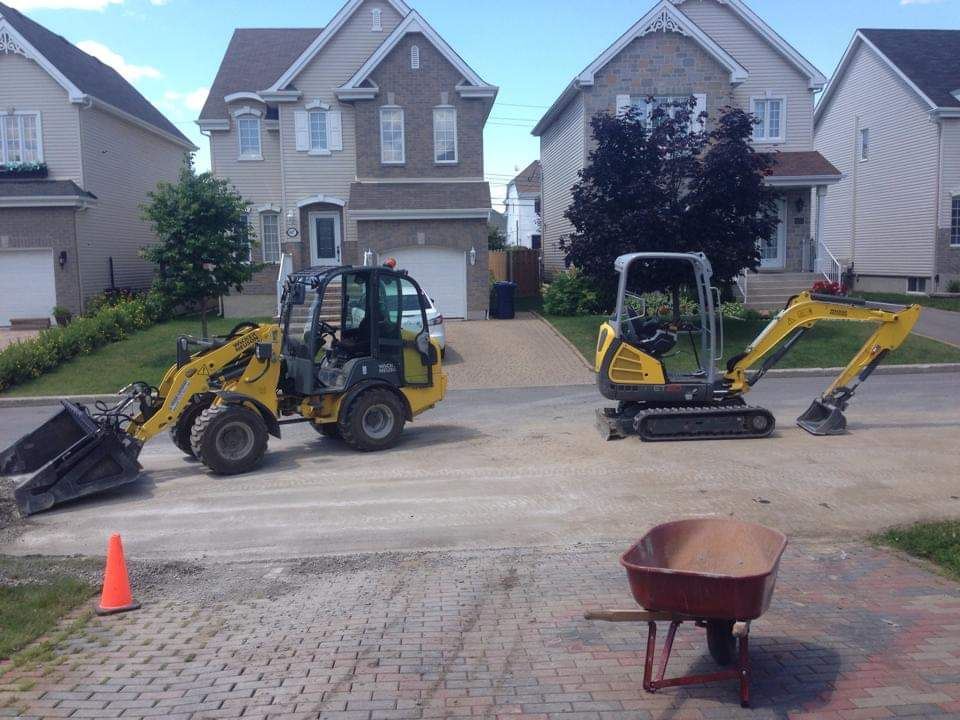 Deux véhicules de chantier sont garés devant une maison