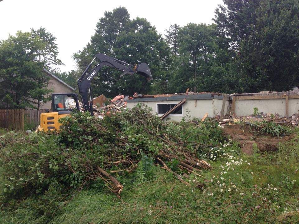 Une maison est démolie par une excavatrice jaune