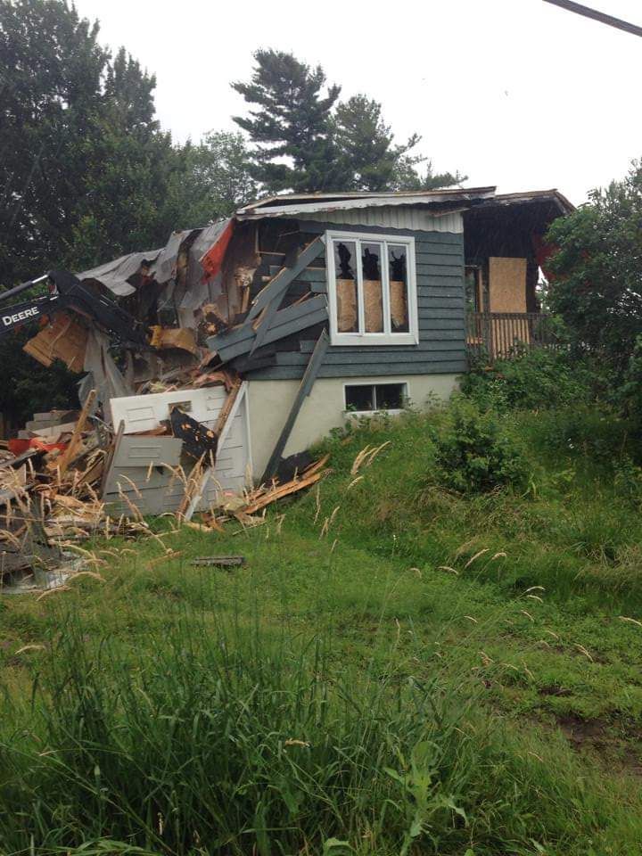 Une maison est en train d'être démolie au milieu d'un champ herbeux