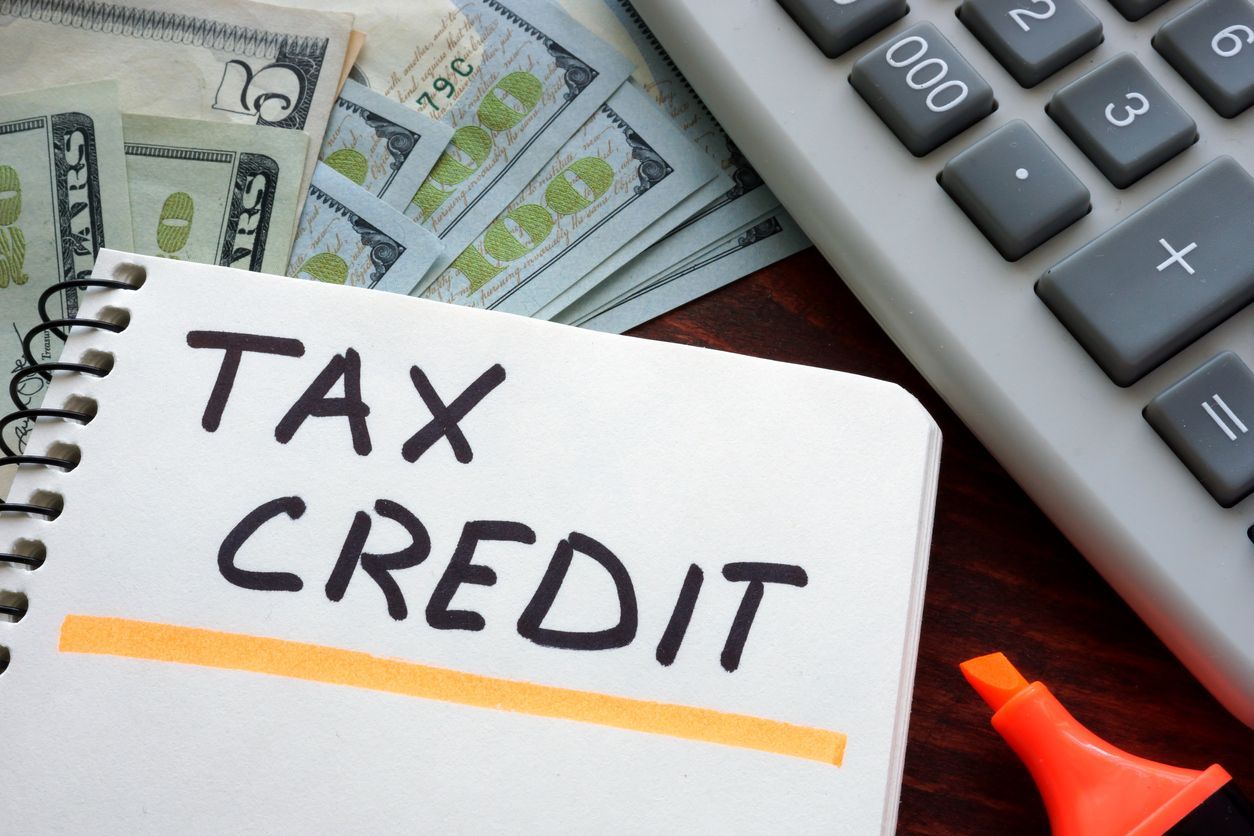 Nebraska property tax credits concept - Tax credit written on a notebook, dollar bills, marker, and calculator on a table.