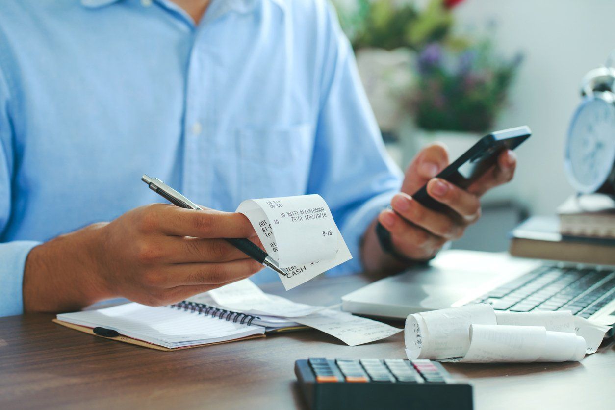 Businessman computing business sales tax - looking at receipts and other documents.