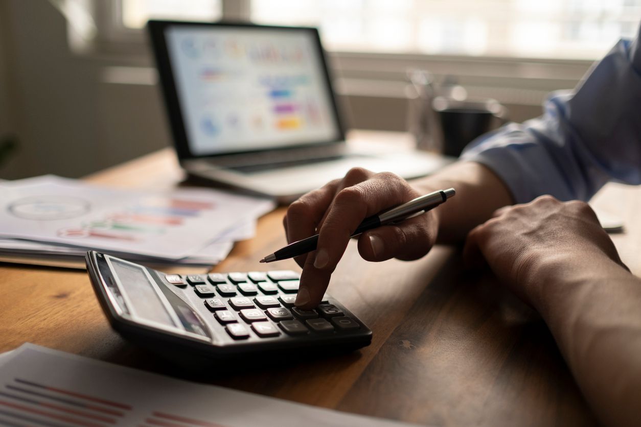 Businessman reviewing company data while computing finances - concept of paying yourself as a business owner.