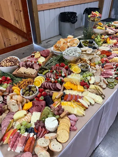Long buffet table with assorted meats, cheeses, fruits, vegetables, and appetizers at an indoor event