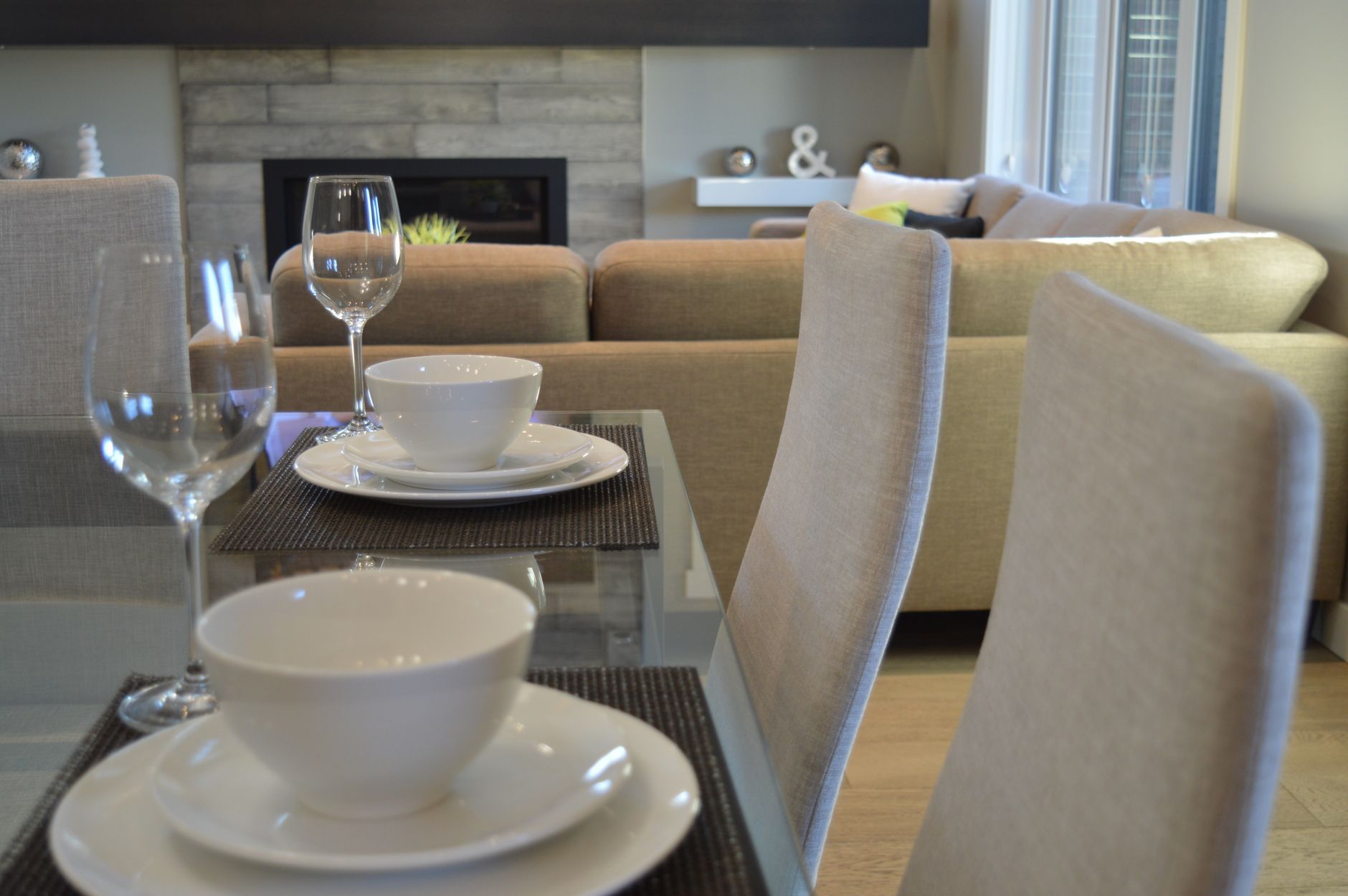 Set dining table in a modern living room with white bowls, plates, and wine glasses