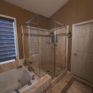 Bathroom with glass-enclosed shower, tiled tub, and beige walls and floor.