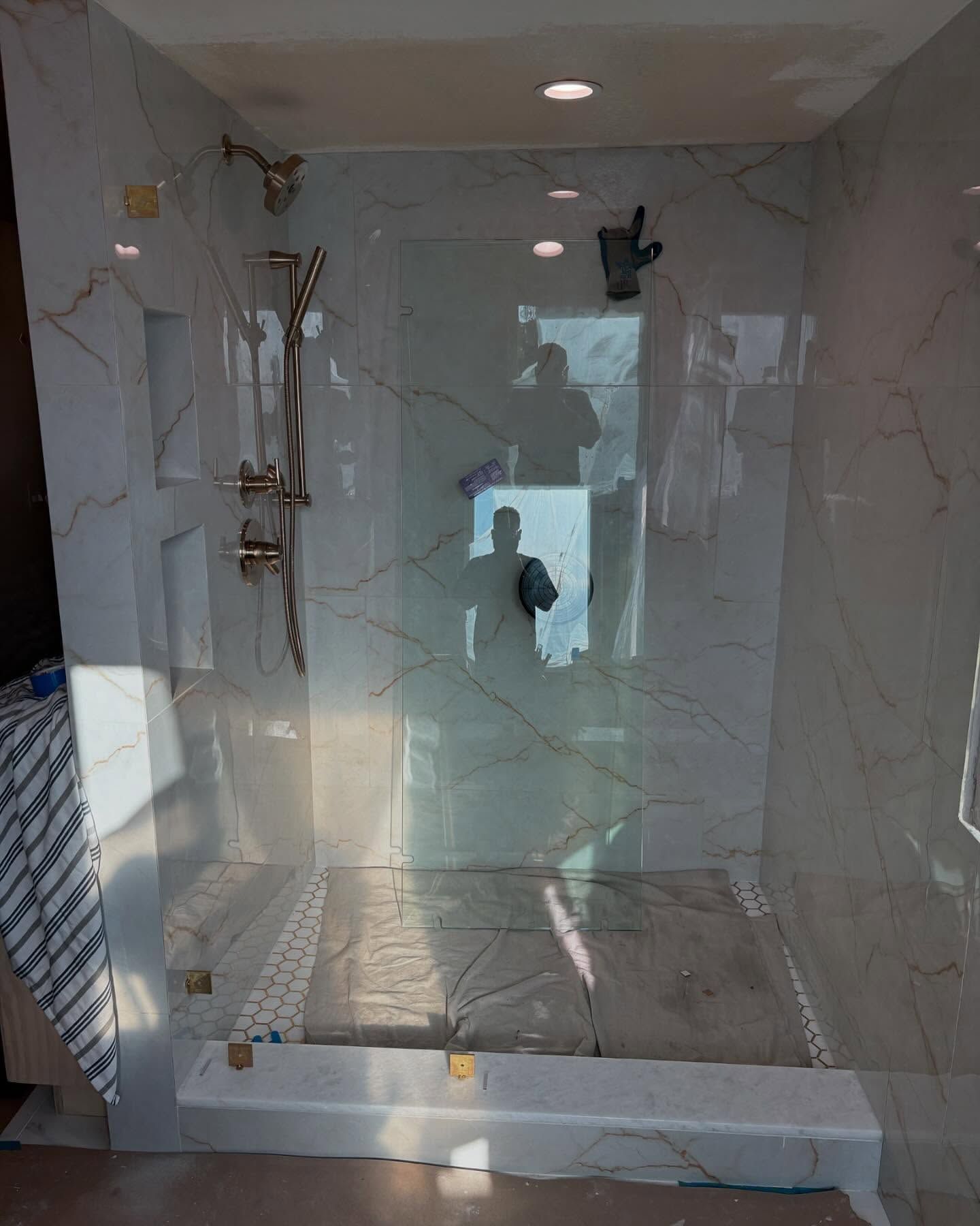 Empty modern shower with white marble-style tiles, glass door, and built-in shower fixtures