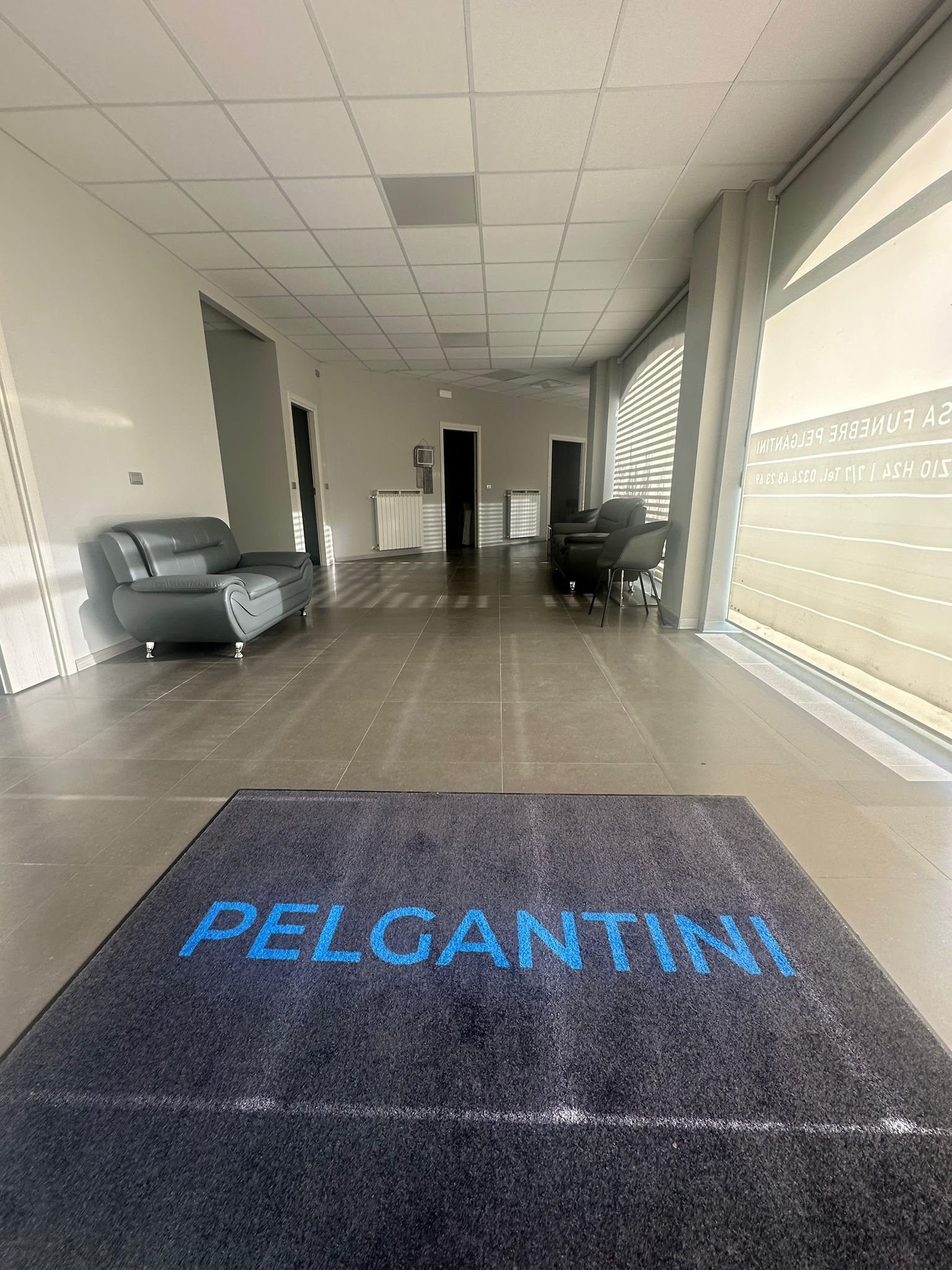 Ingresso con zerbino PELCANTINI, due divani neri e ampie finestre.