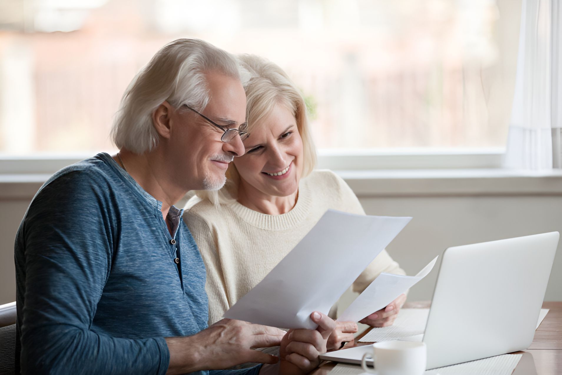 Elderly Couple Sitting At A Table Looking At Papers — Michael Andrews Taxation & Accounting Services In Pacific Paradise, QLD