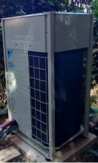 Unità HVAC esterna Daikin, grigio chiaro, con aletta di raffreddamento blu scuro, installata su blocchi di cemento.