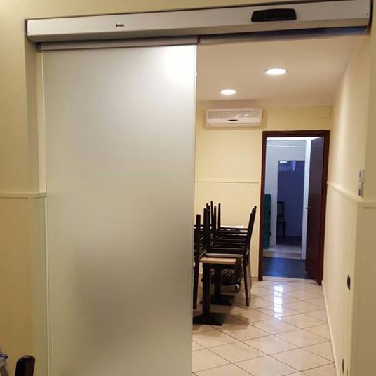 Un corridoio con una porta scorrevole in vetro che conduce alla sala da pranzo
