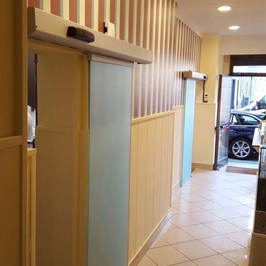 Un corridoio con una porta scorrevole in vetro e un'auto parcheggiata sullo sfondo.