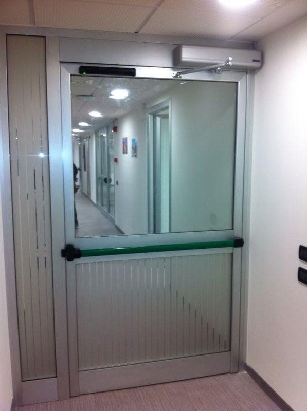Un corridoio con una porta a vetri e una maniglia verde