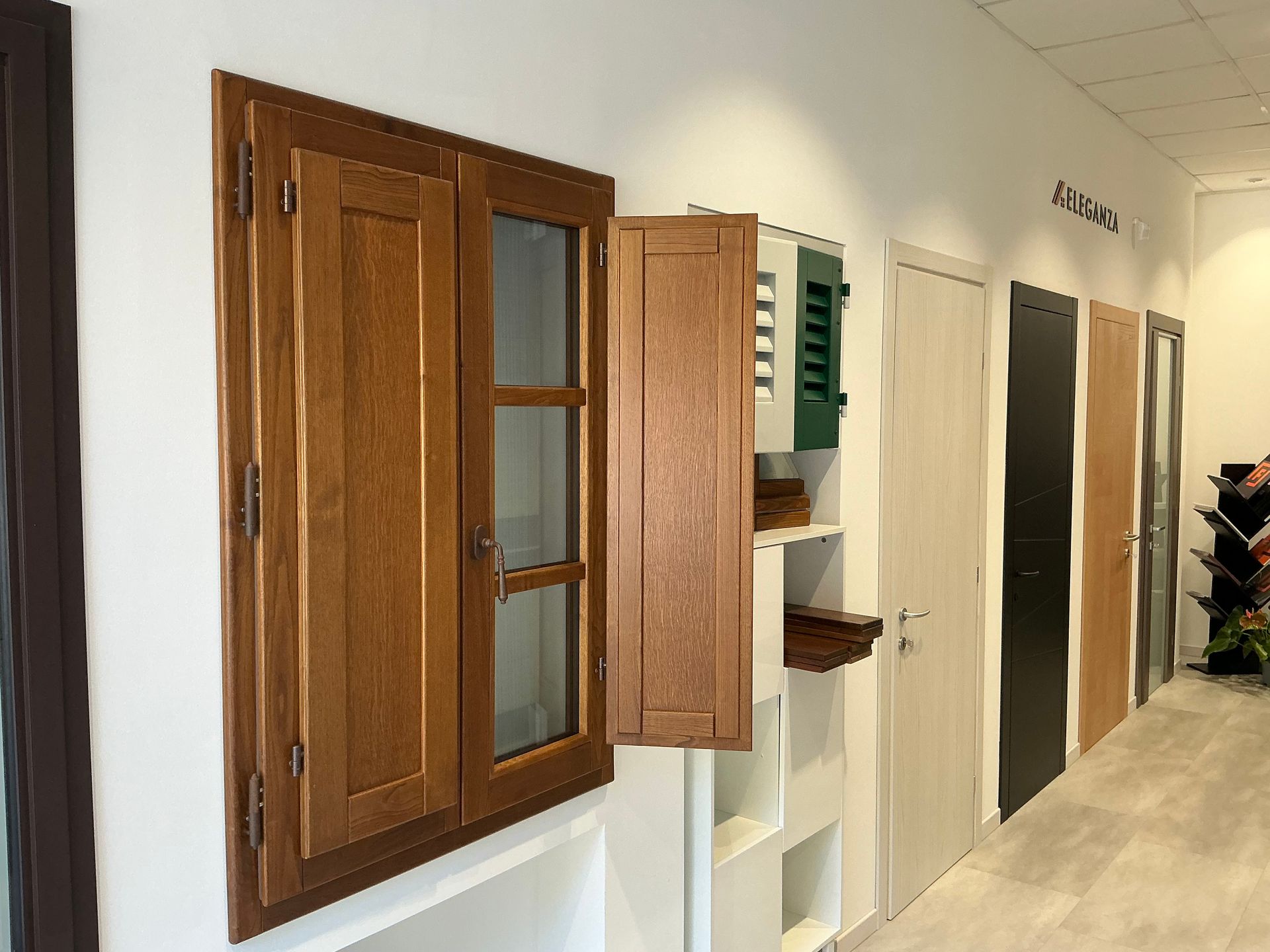 Porte interne esposte in uno showroom, con un bancone della reception e opere d'arte incorniciate.
