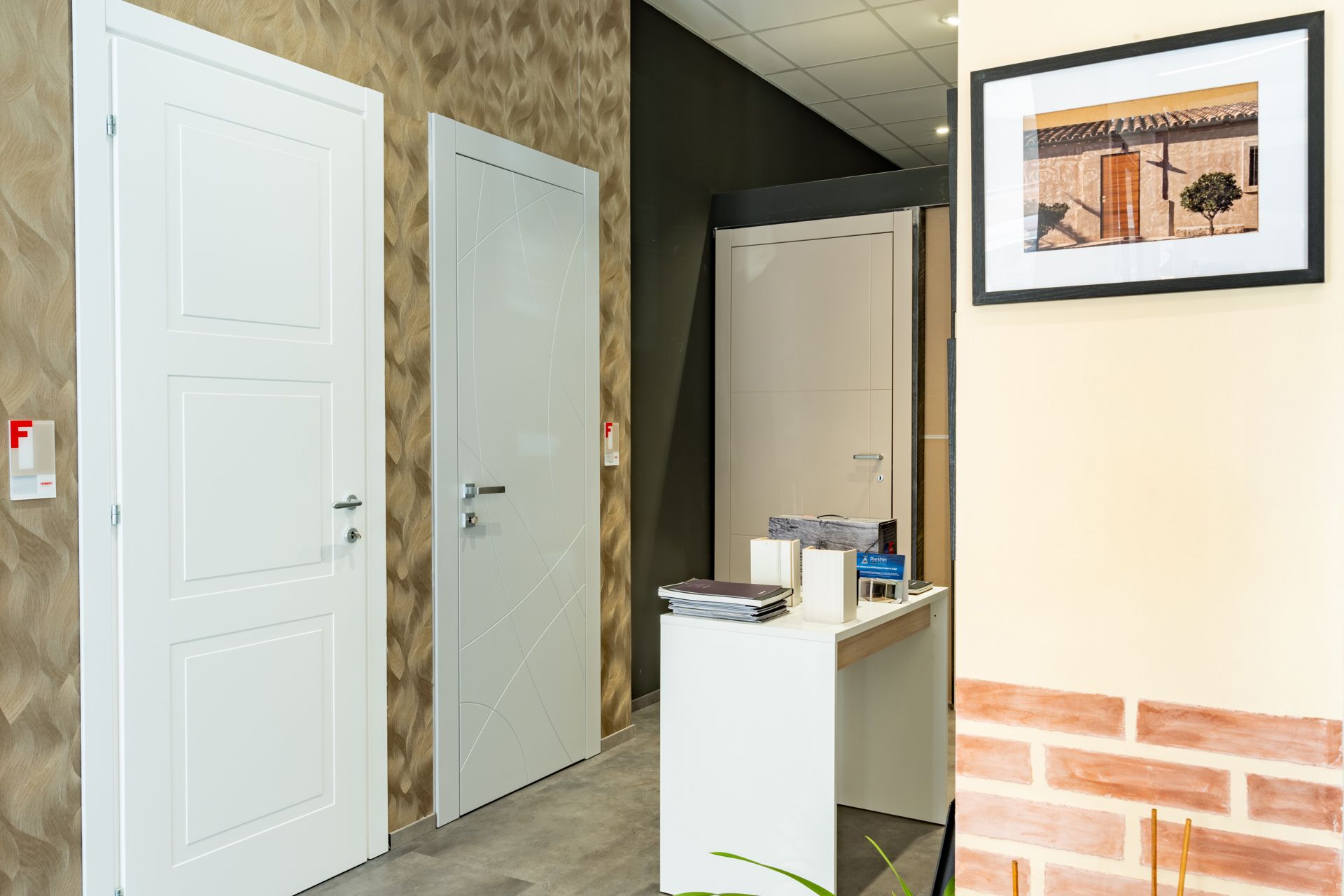 Porte interne esposte in uno showroom, con un bancone della reception e opere d'arte incorniciate.