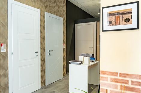 Porte interne esposte in uno showroom, con un bancone della reception e opere d'arte incorniciate.