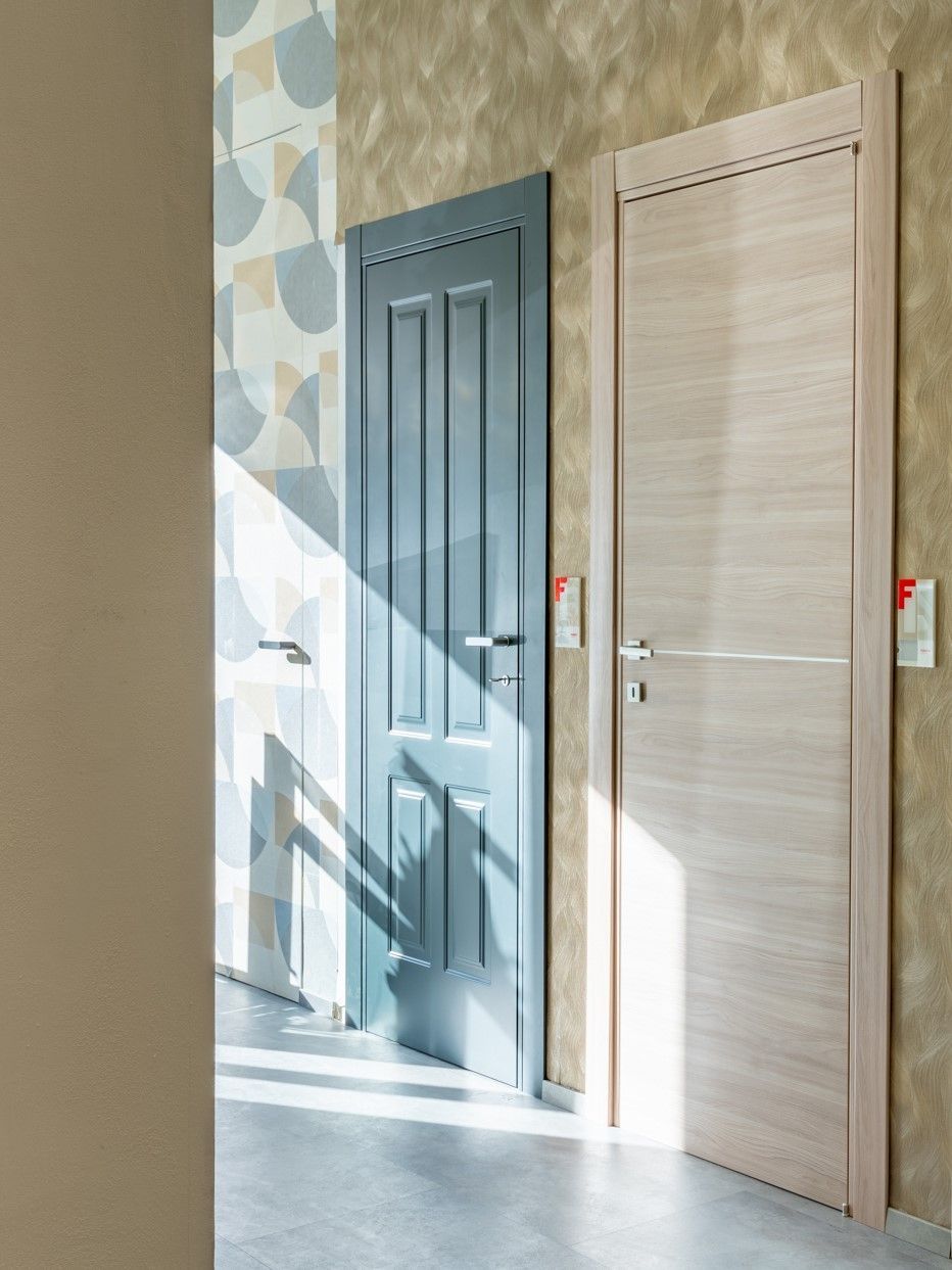 Due porte interne, una blu e una in legno chiaro, esposte contro pareti decorate.