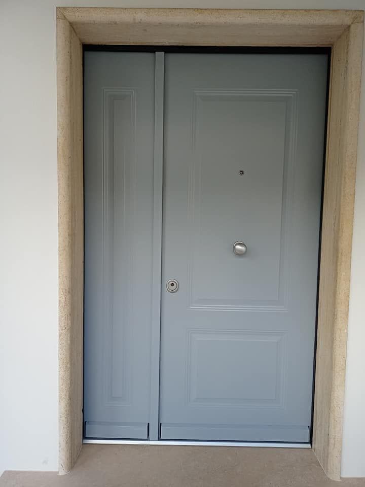 Porta grigia con pannello laterale in cornice di pietra.