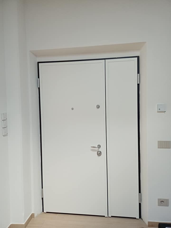 Porta bianca con finiture nere in un corridoio bianco.