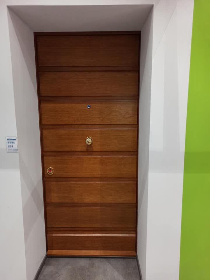 Porta in legno con pannelli orizzontali, inserita in una cornice bianca e con pomelli dorati.
