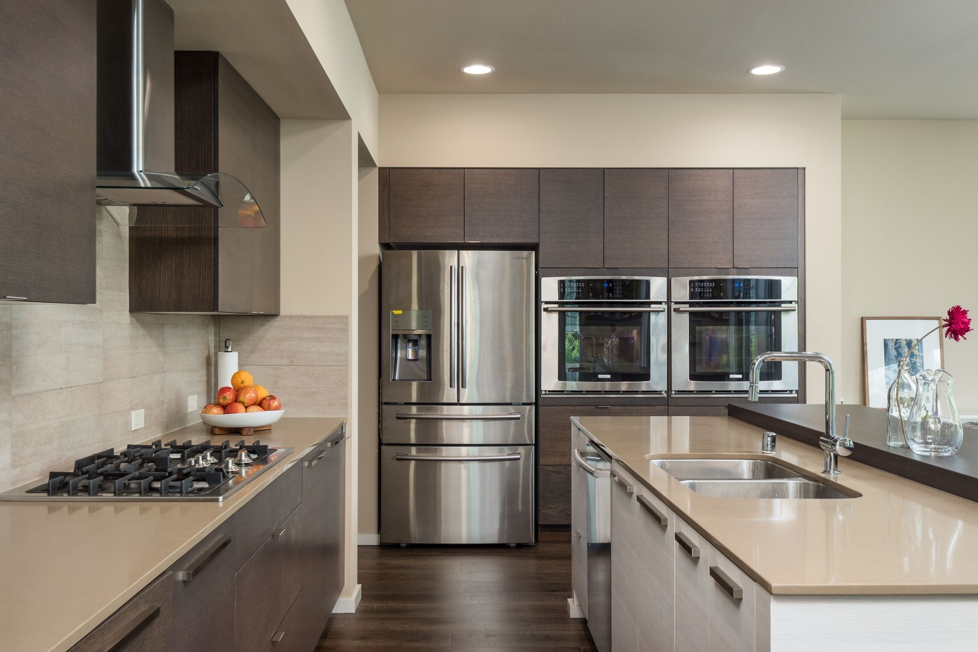 Modern kitchen with stainless steel appliances, dark cabinets, and light countertops.