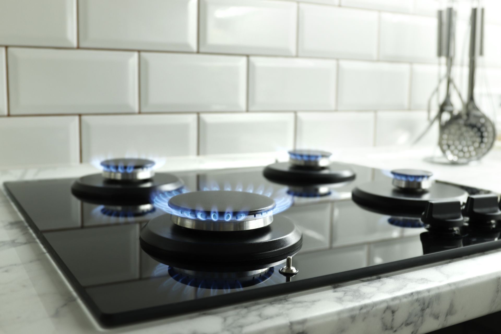 Gas stovetop with blue flames burning.