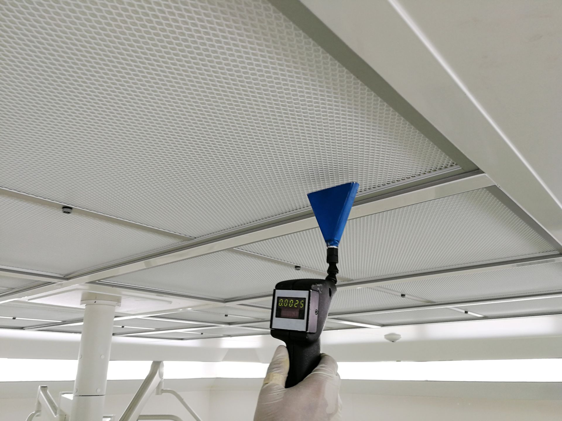 A person is holding a blue cone in front of a ceiling.