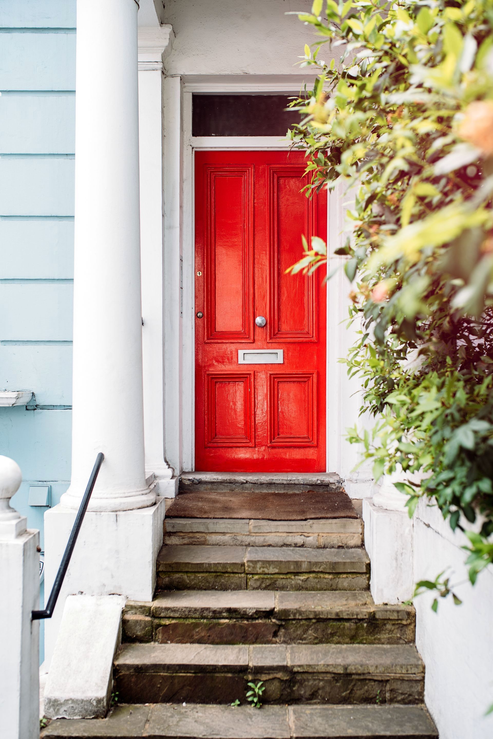 A red front door with stairs leading up to it.