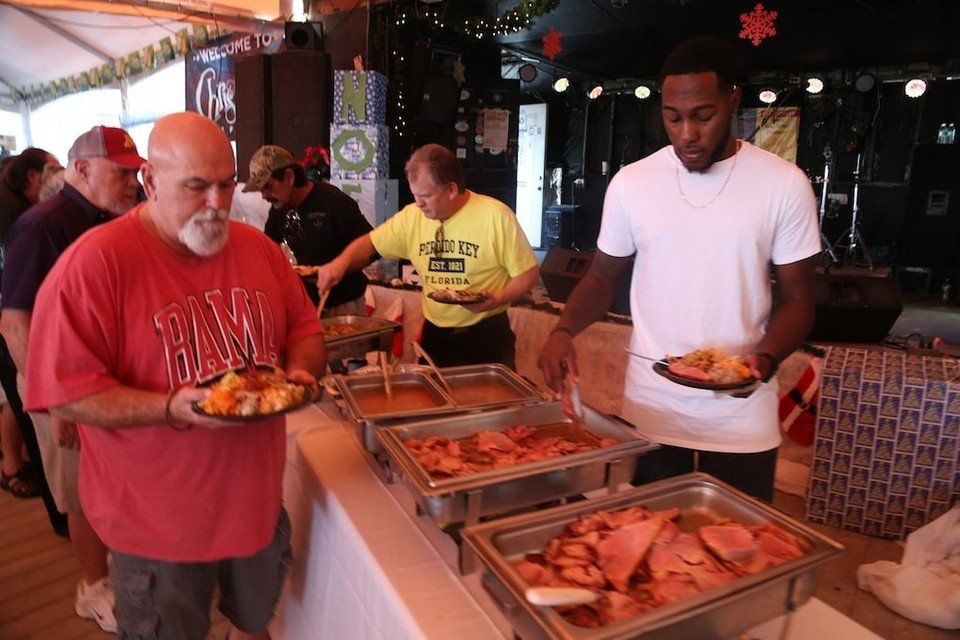 People serving themselves food from buffet trays at an indoor gathering.